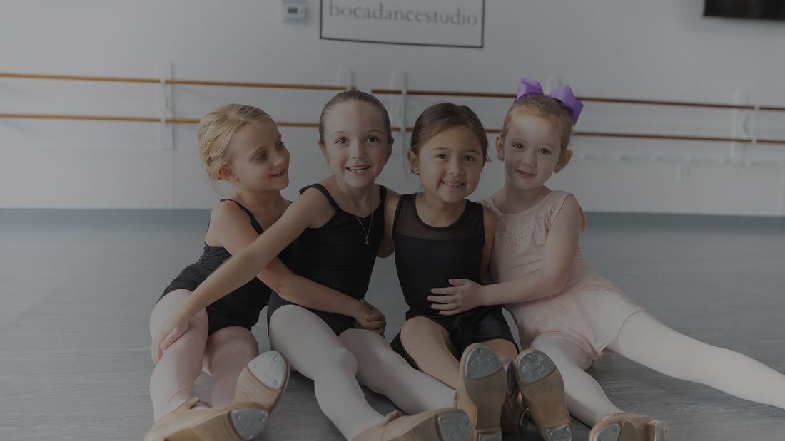 Young dancers sitting together on the studio floor at Boca Dance Studio